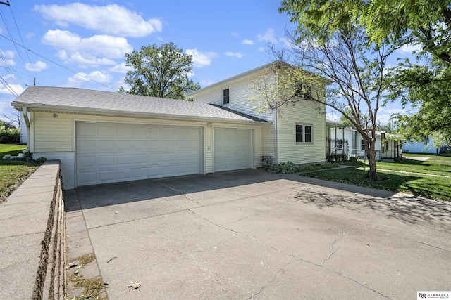 traditional-style house featuring a front lawn, a garage, driveway, and a shingled roof