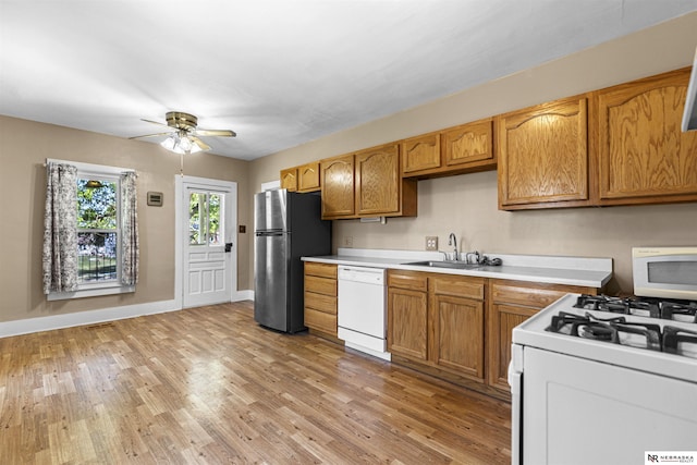 kitchen featuring white appliances, a sink, light countertops, and light wood-type flooring