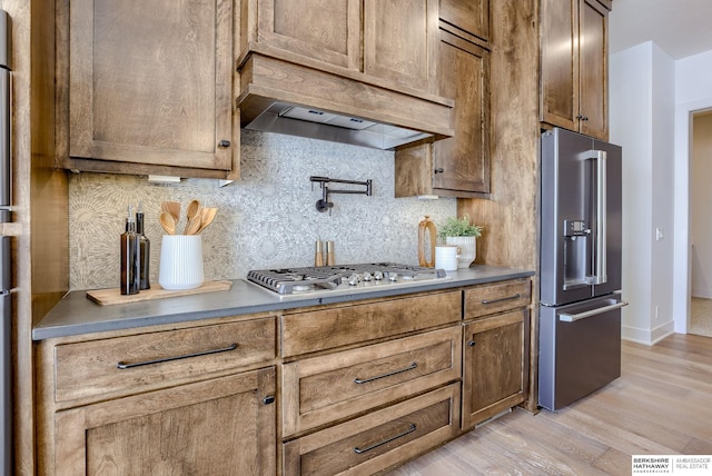 6511 Garvin St, Omaha, NE 68152 - kitchen with light wood-style floors, custom exhaust hood, tasteful backsplash, and appliances with stainless steel finishes