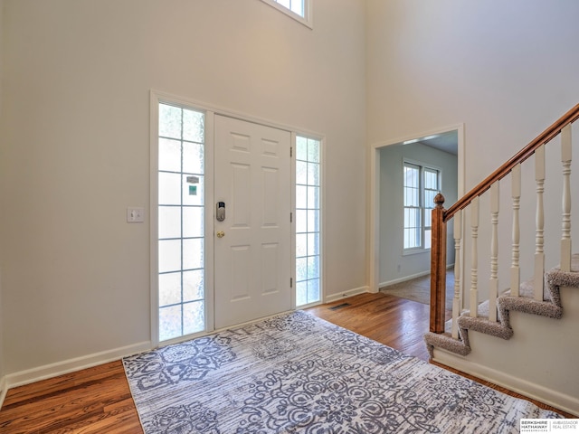 foyer featuring stairs, a high ceiling, baseboards, and wood finished floors