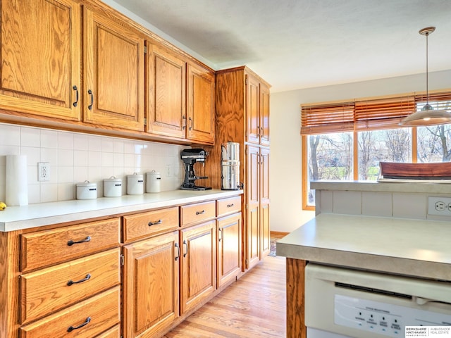 kitchen with tasteful backsplash, light countertops, light wood-type flooring, and dishwasher