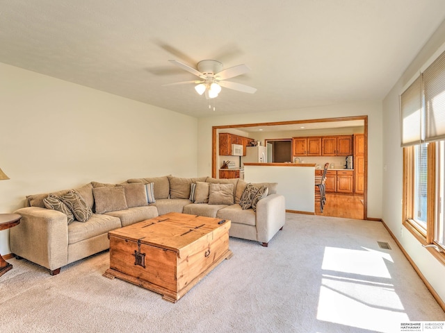 living area with visible vents, light colored carpet, and ceiling fan
