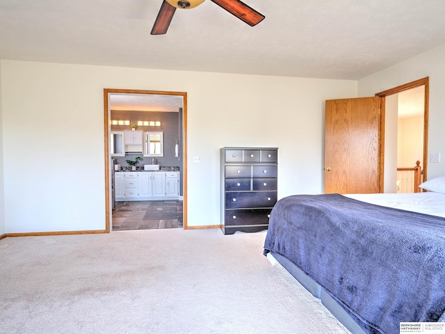 carpeted bedroom with baseboards, connected bathroom, and ceiling fan
