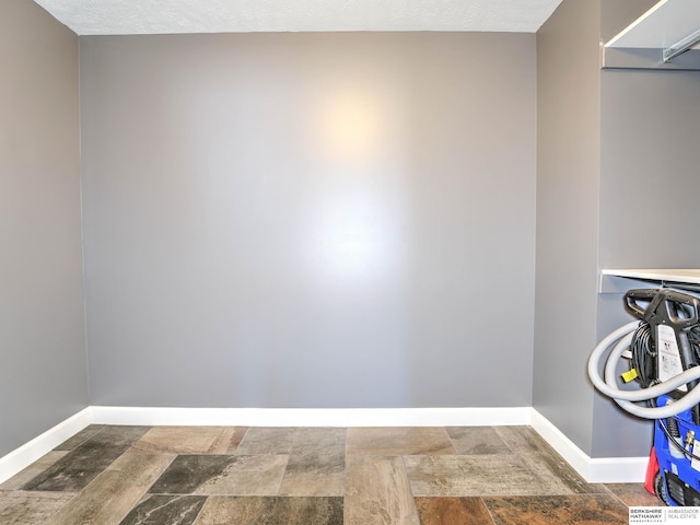 clothes washing area featuring stone finish floor and baseboards