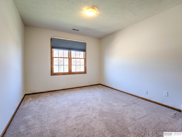 spare room featuring carpet flooring, baseboards, and visible vents