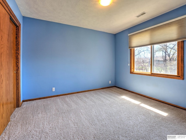 spare room featuring visible vents, baseboards, and carpet flooring