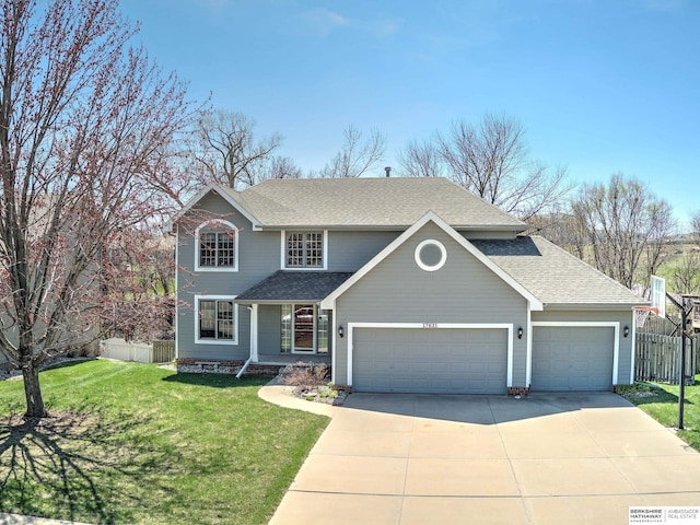traditional home featuring roof with shingles, a front yard, fence, an attached garage, and driveway