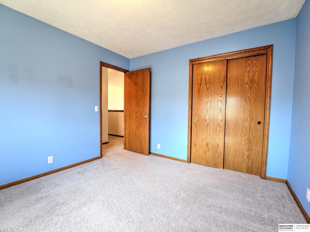 unfurnished bedroom featuring a closet, baseboards, carpet, and a textured ceiling