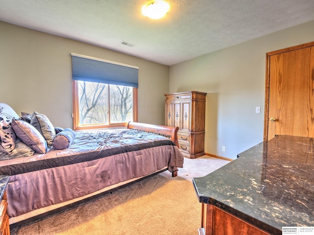 bedroom with a textured ceiling, light colored carpet, and visible vents
