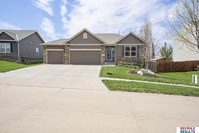 craftsman-style house with a front lawn, stone siding, concrete driveway, fence, and a garage