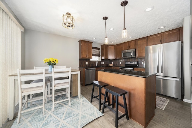 kitchen featuring a center island, a sink, decorative backsplash, light wood-style floors, and stainless steel appliances