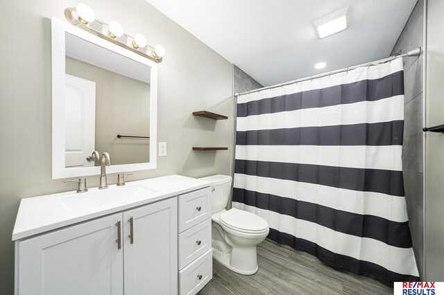 bathroom with curtained shower, wood finished floors, toilet, and vanity