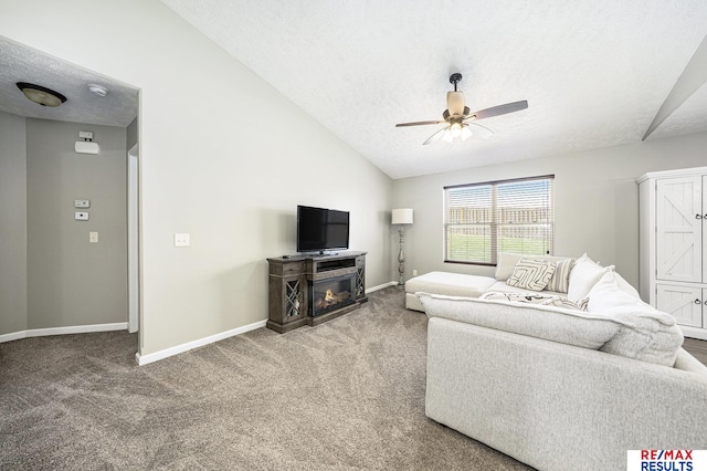 living area featuring vaulted ceiling, a textured ceiling, a ceiling fan, and carpet floors