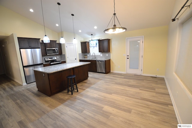 kitchen with tasteful backsplash, a sink, dark brown cabinetry, stainless steel appliances, and a kitchen island