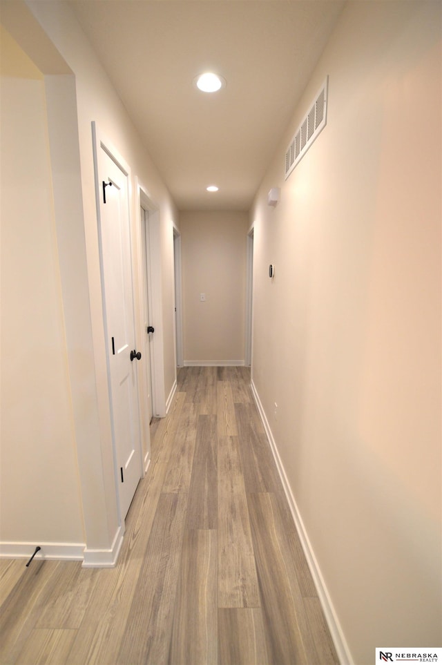 hallway featuring visible vents, baseboards, recessed lighting, and wood finished floors