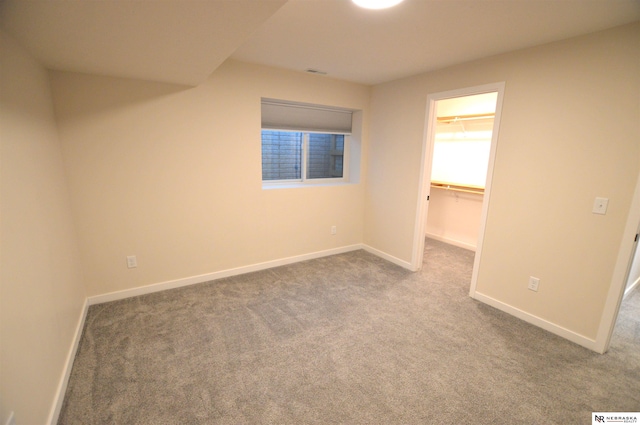 unfurnished bedroom with baseboards, a closet, a spacious closet, carpet floors, and visible vents