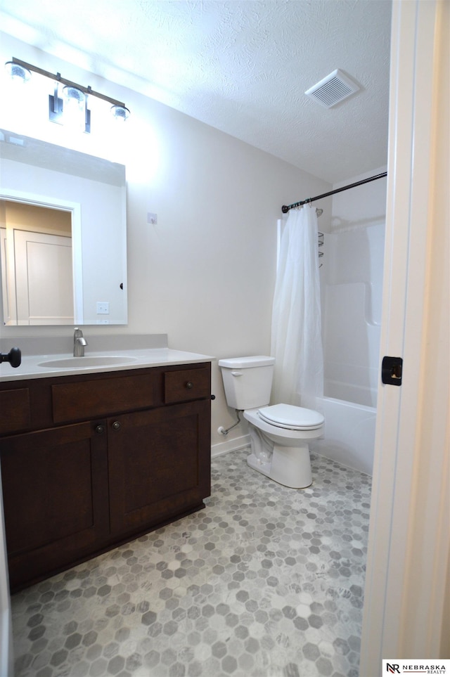 full bath featuring a textured ceiling, vanity, visible vents, toilet, and baseboards