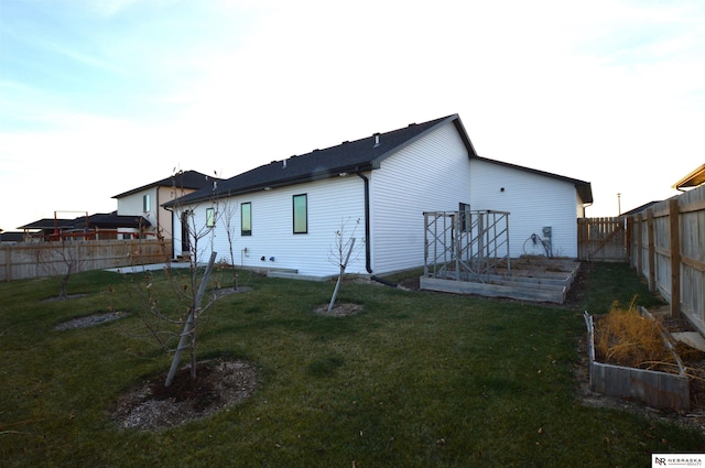 back of property with a garden, a fenced backyard, and a lawn