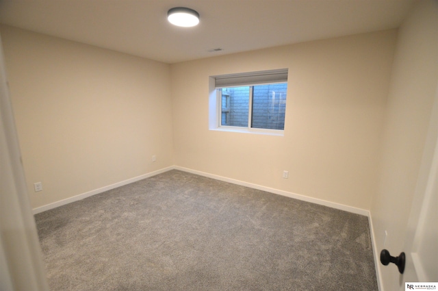 empty room with visible vents, dark colored carpet, and baseboards