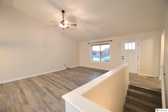 interior space with baseboards, wood finished floors, vaulted ceiling, and a ceiling fan