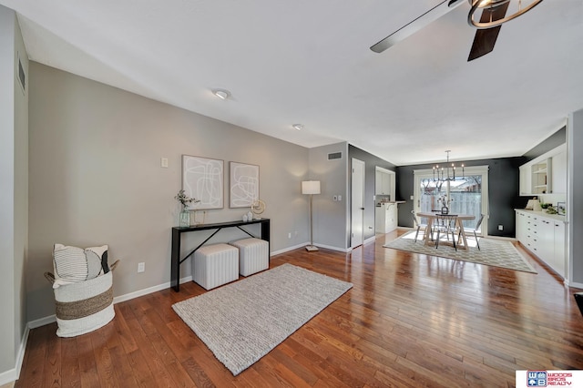 interior space with wood-type flooring, baseboards, visible vents, and ceiling fan with notable chandelier