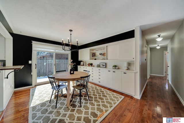 dining area featuring baseboards, a notable chandelier, and hardwood / wood-style flooring