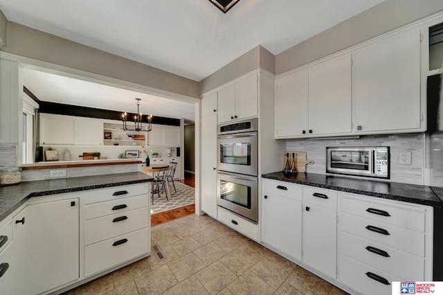 kitchen featuring white cabinets, open shelves, an inviting chandelier, backsplash, and stainless steel double oven