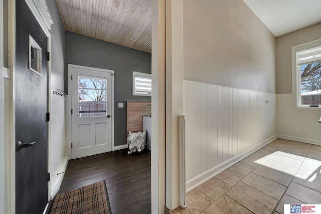doorway to outside featuring a wainscoted wall and baseboards