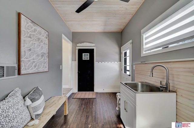 interior space with a ceiling fan, wainscoting, dark wood finished floors, wood ceiling, and a sink