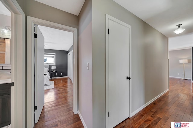 hallway with dark wood-type flooring and baseboards