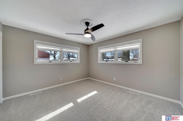 carpeted spare room featuring visible vents, baseboards, and a ceiling fan