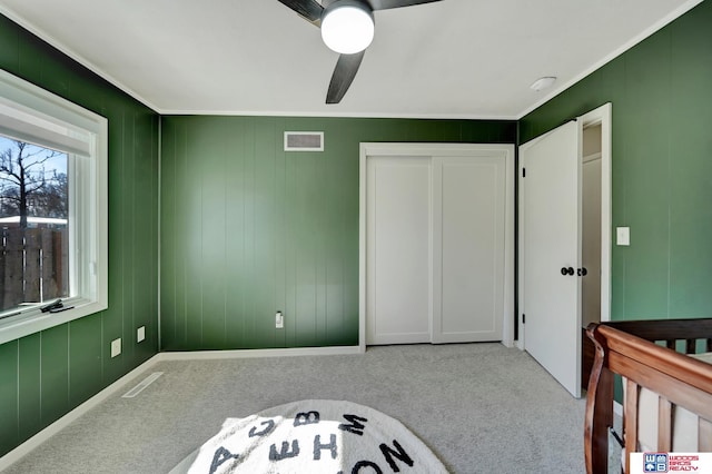 unfurnished bedroom featuring crown molding, visible vents, ceiling fan, and carpet flooring