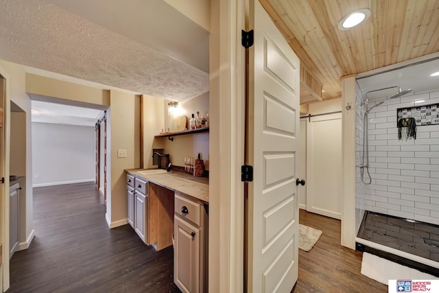 bathroom with baseboards, recessed lighting, vanity, wood finished floors, and tiled shower