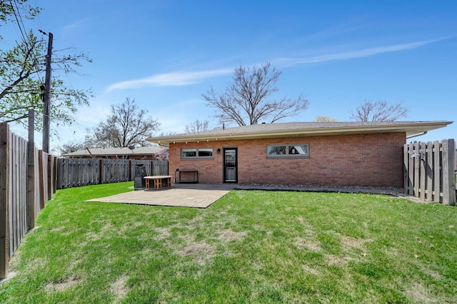 back of house featuring a yard, brick siding, a fenced backyard, and a patio