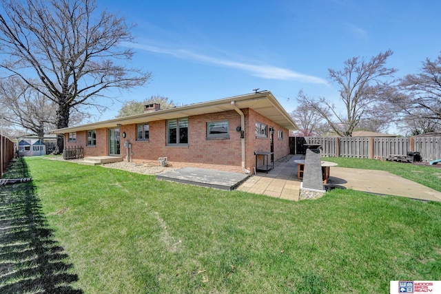back of house featuring a yard, brick siding, a fenced backyard, and a patio area