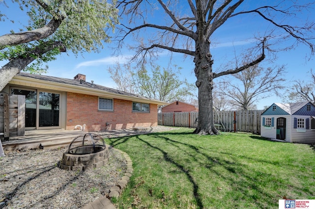 view of yard featuring a fenced backyard, an outdoor structure, and an outdoor fire pit