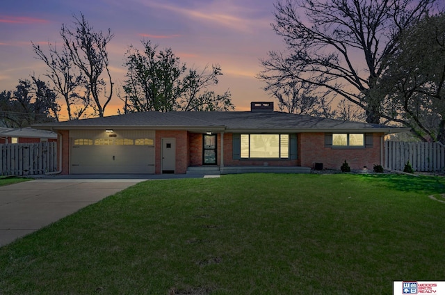 view of front of property with an attached garage, fence, concrete driveway, brick siding, and a front lawn