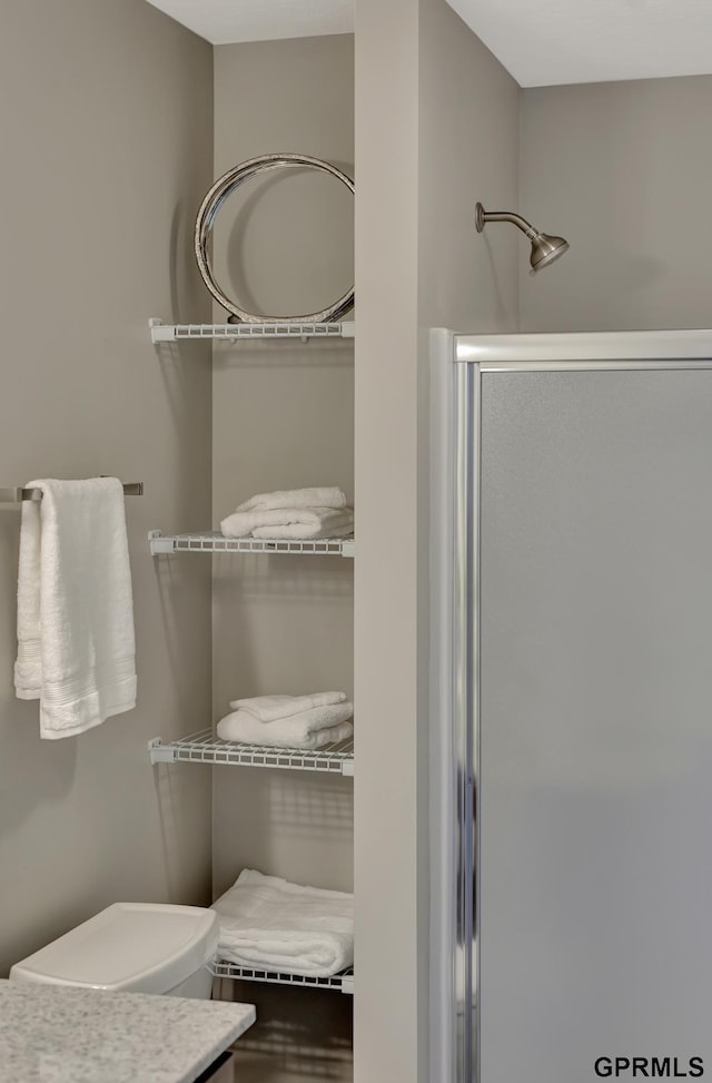 bathroom with toilet, vanity, and a shower with door