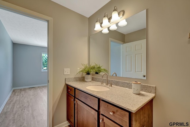 bathroom with wood finished floors, vanity, and baseboards