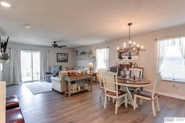dining area with visible vents, baseboards, wood finished floors, and ceiling fan with notable chandelier