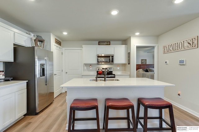 kitchen with stainless steel appliances, light wood-style floors, a breakfast bar, and white cabinetry