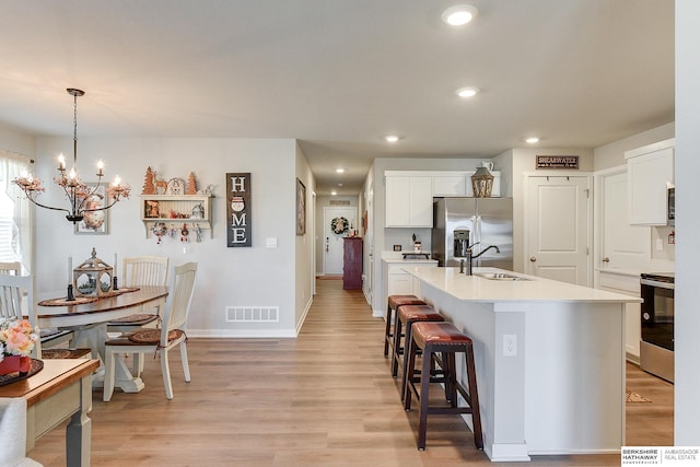 kitchen featuring visible vents, a sink, light countertops, light wood-type flooring, and stainless steel appliances