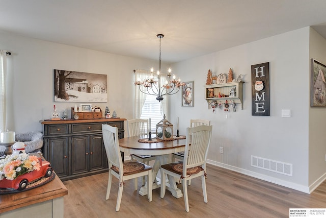 dining room with light wood-style floors, visible vents, baseboards, and an inviting chandelier
