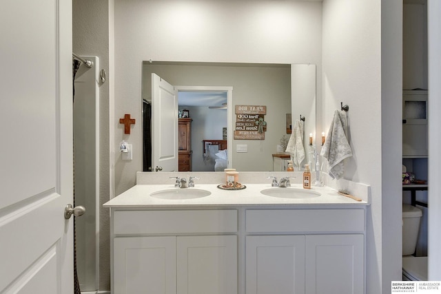 ensuite bathroom featuring a sink, ensuite bathroom, toilet, and double vanity