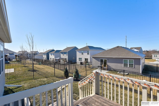 wooden terrace featuring a residential view, a fenced backyard, and a yard