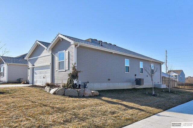 view of home's exterior featuring central AC, a garage, fence, and a lawn