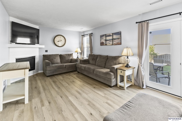 living room featuring a glass covered fireplace and light wood-type flooring