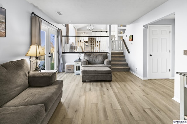 living area with a chandelier, wood finished floors, baseboards, and stairway