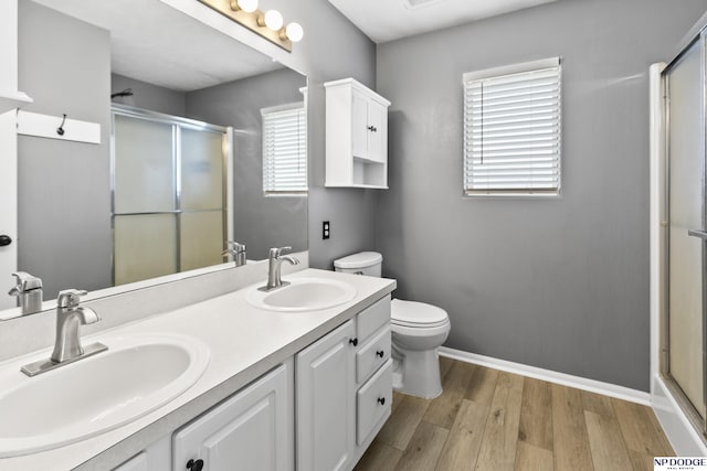 full bathroom featuring a shower stall, wood finished floors, toilet, double vanity, and baseboards