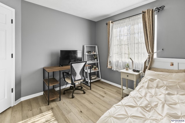 bedroom featuring wood finished floors, baseboards, and an office area